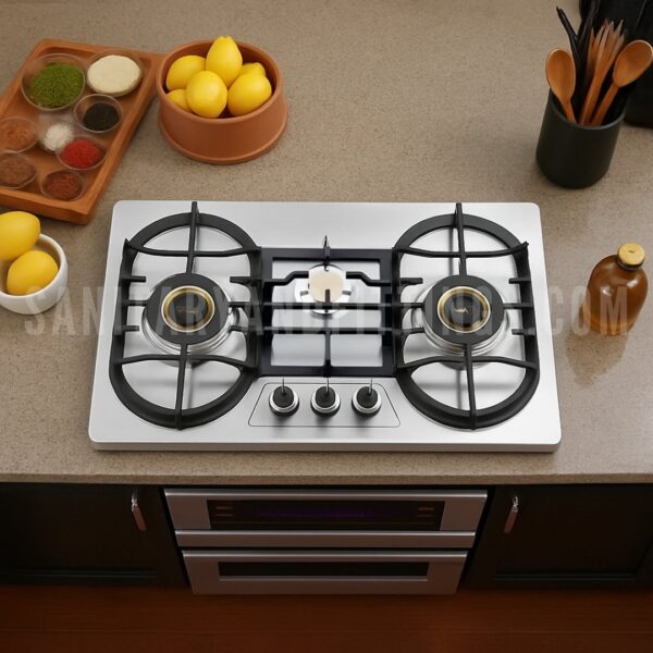 Gas Stove RINO RS959B,"Stainless steel kitchen stove with three burners and control knobs, illuminated by overhead lighting,