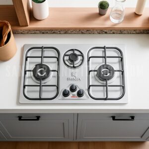 "Stainless steel kitchen stove with three burners and control knobs, illuminated by overhead lighting,